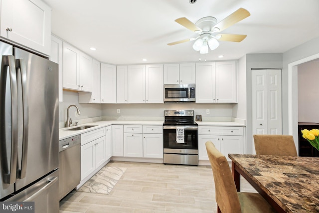 kitchen featuring recessed lighting, light countertops, appliances with stainless steel finishes, white cabinets, and a sink