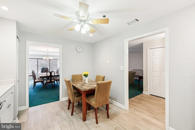 dining space featuring visible vents, light wood-style flooring, baseboards, and ceiling fan with notable chandelier