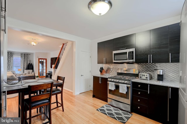 kitchen with open floor plan, stainless steel appliances, light countertops, and dark cabinets