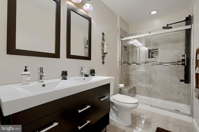 full bath featuring double vanity, a sink, toilet, and a shower stall