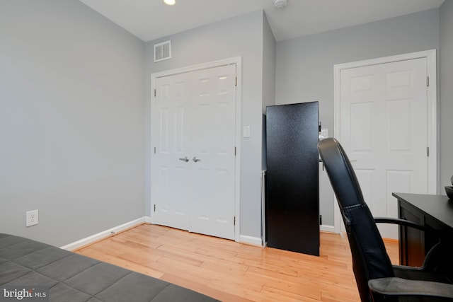 unfurnished office with wood finished floors, visible vents, and baseboards