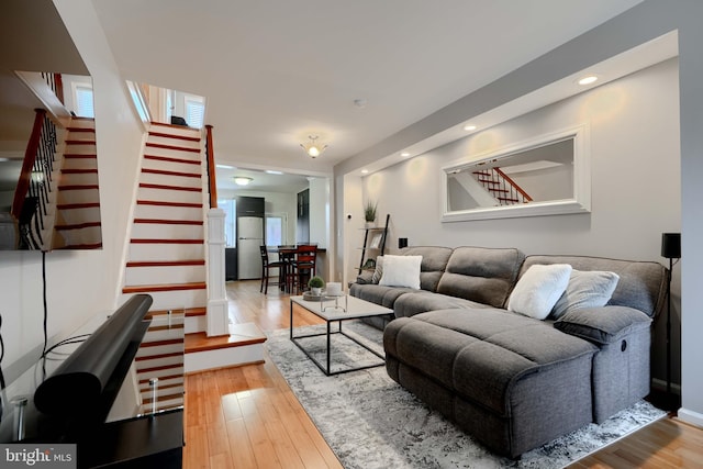 living room featuring stairs, baseboards, wood finished floors, and recessed lighting