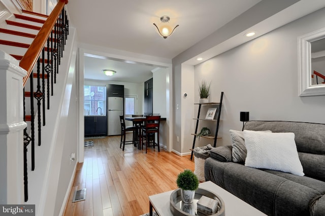 living room with recessed lighting, visible vents, wood finished floors, baseboards, and stairs