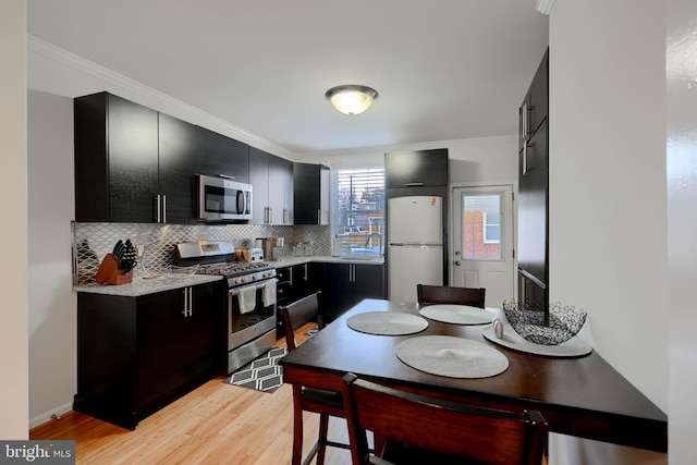 kitchen with backsplash, appliances with stainless steel finishes, light countertops, and dark cabinets