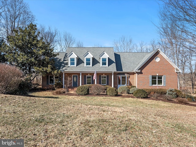 cape cod home featuring a front yard, covered porch, and brick siding