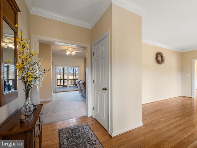 hallway with baseboards, light wood-type flooring, and crown molding