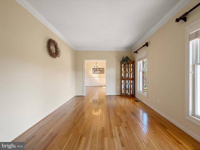 unfurnished room featuring light wood-type flooring, baseboards, and crown molding