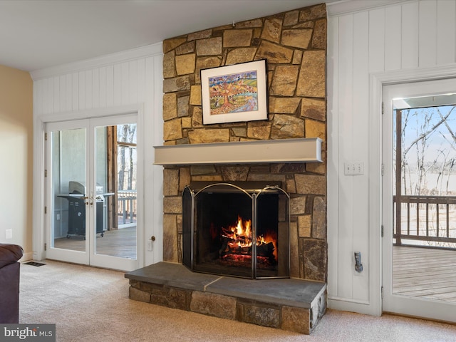 interior details with carpet floors, a stone fireplace, and french doors