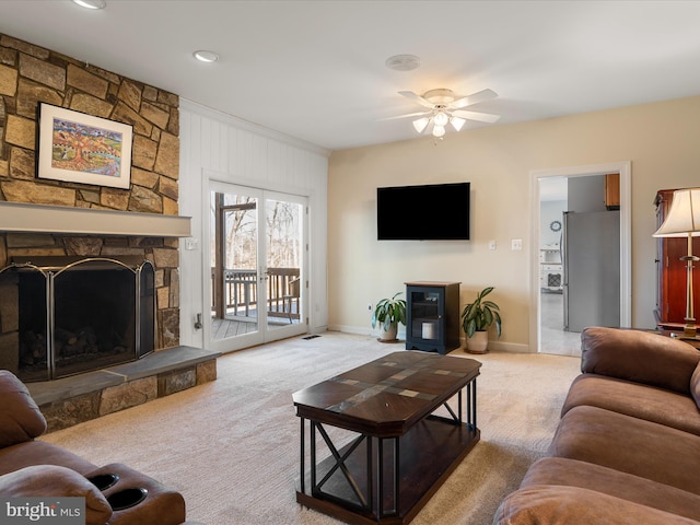 living room with a ceiling fan, light carpet, a fireplace, and baseboards