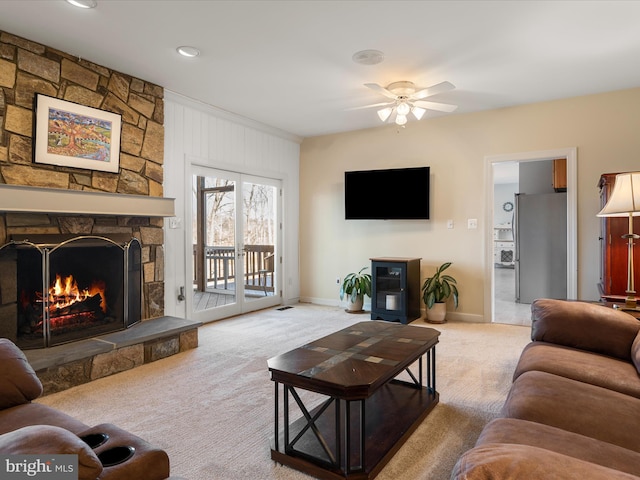 carpeted living area with ceiling fan, a fireplace, and baseboards