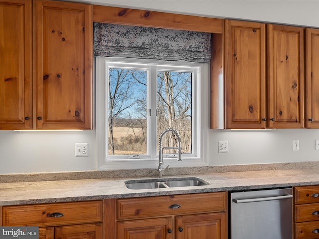 kitchen with dishwasher, brown cabinetry, and a sink