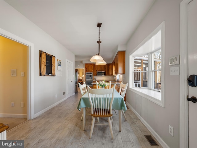 dining space with light wood finished floors, visible vents, and baseboards