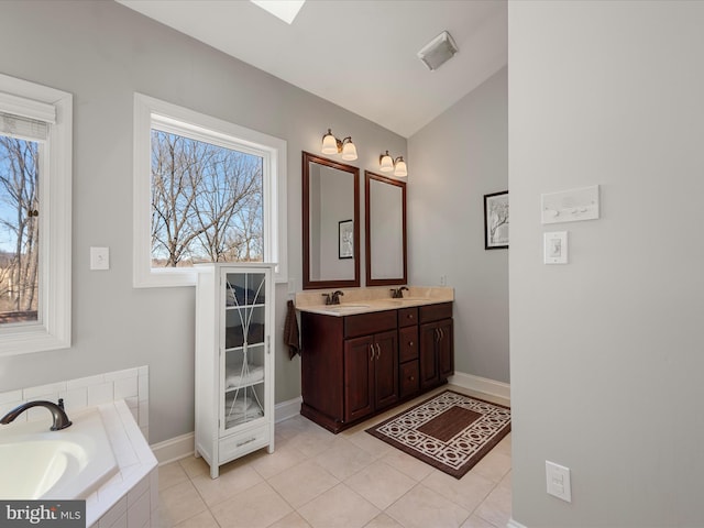 bathroom featuring tiled bath, a sink, baseboards, tile patterned floors, and double vanity