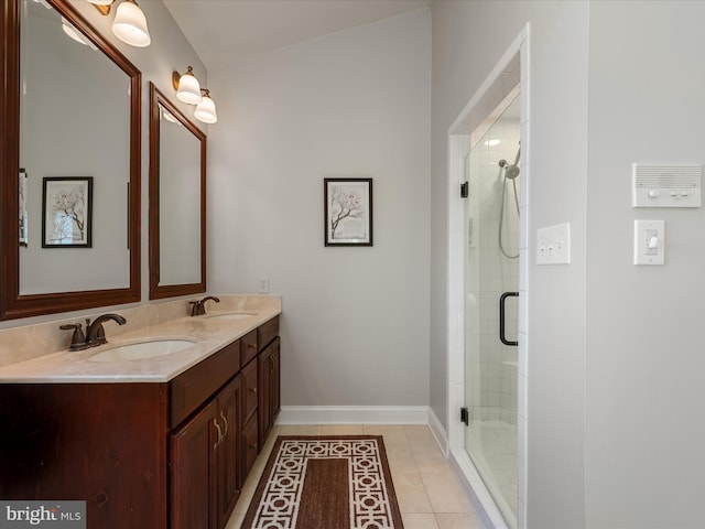 bathroom featuring double vanity, a stall shower, baseboards, tile patterned floors, and a sink