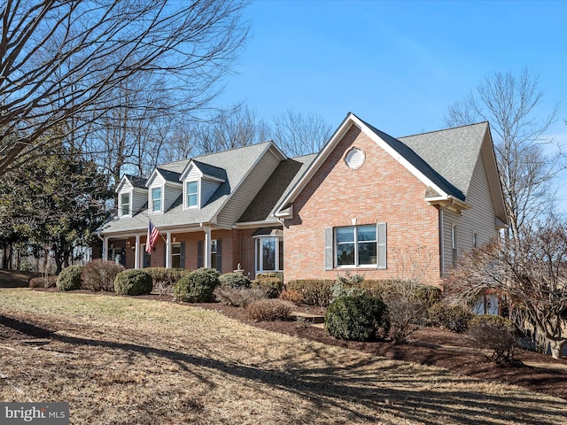 view of front of house with a front yard, a porch, and brick siding