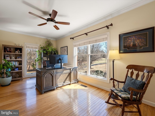 home office with light wood-style floors, crown molding, baseboards, and a wealth of natural light