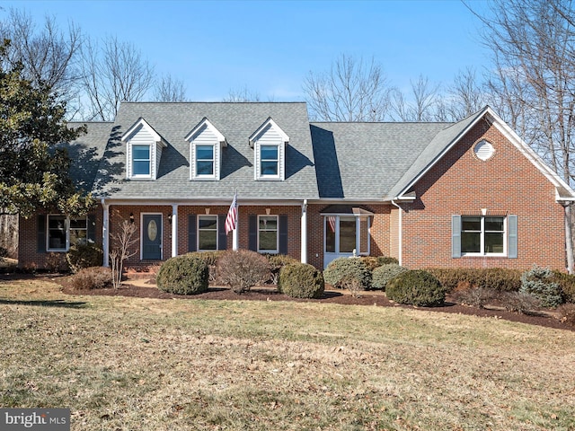 cape cod-style house with brick siding, a shingled roof, and a front yard