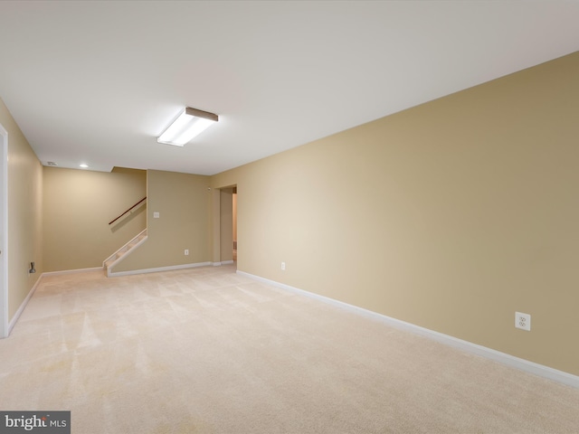 finished below grade area with light colored carpet, baseboards, and stairs