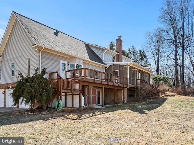 rear view of house featuring a garage, a sunroom, a chimney, roof with shingles, and a deck