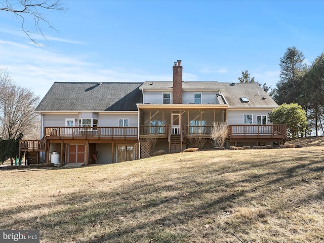 back of house with a sunroom, a deck, and a lawn