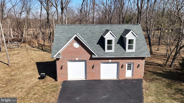 view of front facade featuring brick siding, a detached garage, and a shingled roof