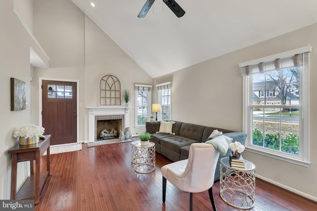 living area featuring high vaulted ceiling, wood-type flooring, a wealth of natural light, and baseboards