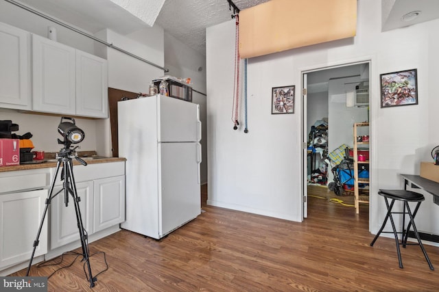 kitchen with white fridge, white cabinetry, dark hardwood / wood-style floors, and a textured ceiling