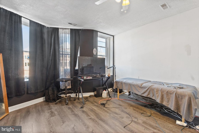 bedroom featuring hardwood / wood-style flooring, ceiling fan, and a textured ceiling