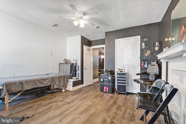 bedroom with hardwood / wood-style flooring, ceiling fan, and a textured ceiling