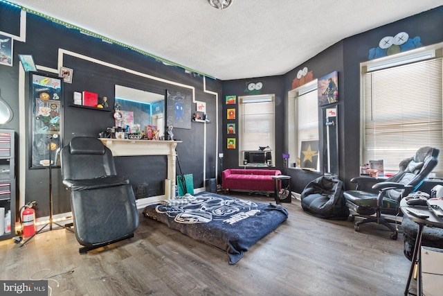 living area with a fireplace, a textured ceiling, and hardwood / wood-style flooring