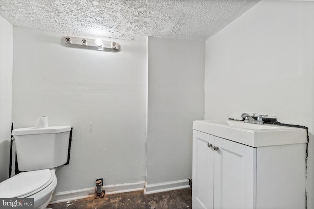 bathroom with toilet, vanity, and a textured ceiling