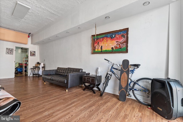 living room featuring a wall unit AC, wood-type flooring, and a textured ceiling