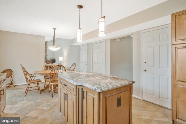 kitchen with light stone countertops, a kitchen island, baseboards, and pendant lighting