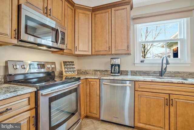 kitchen with light stone countertops, stainless steel appliances, and a sink