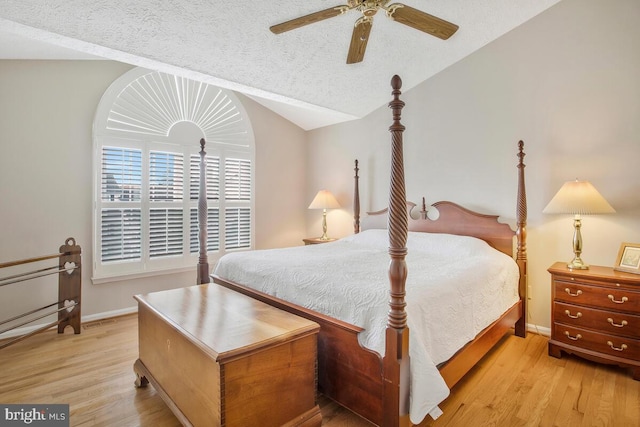 bedroom featuring light wood-type flooring, lofted ceiling, a textured ceiling, and baseboards