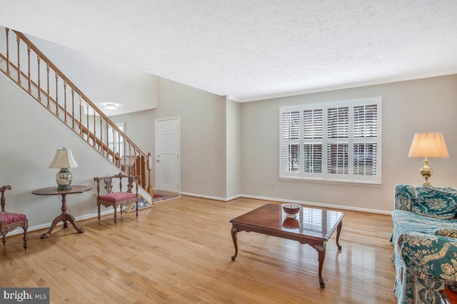 living room with light wood finished floors, baseboards, and stairway