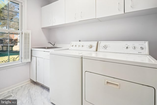 washroom featuring a sink, a healthy amount of sunlight, washer and dryer, marble finish floor, and cabinet space