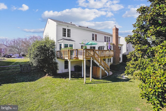 rear view of property featuring a lawn, a chimney, stairway, fence, and a wooden deck