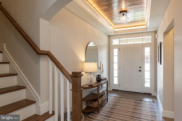 entryway featuring wood ceiling, wood-type flooring, and a raised ceiling