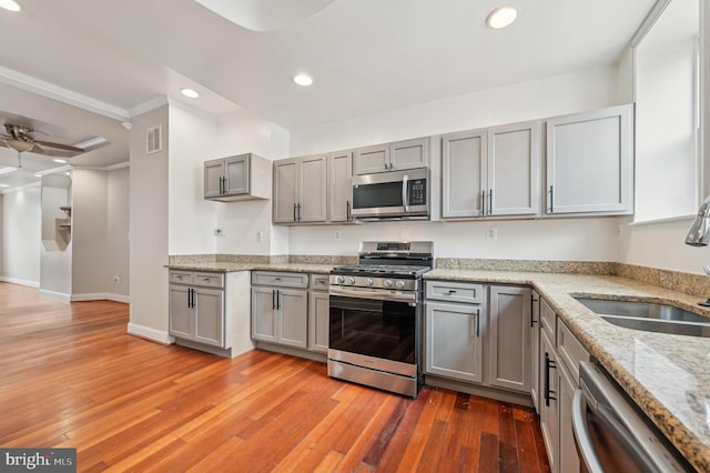 kitchen with stainless steel appliances, visible vents, light wood-style flooring, gray cabinetry, and a sink