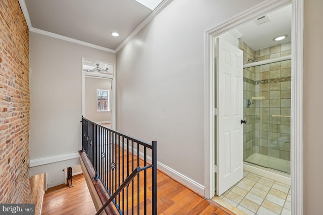 corridor featuring ornamental molding, baseboards, an upstairs landing, and wood finished floors