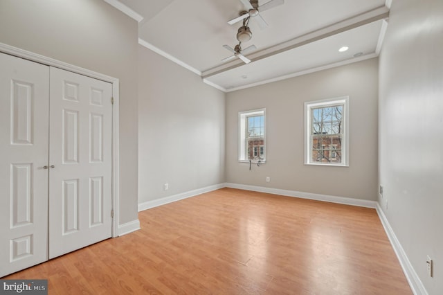 empty room with light wood-style floors, baseboards, and crown molding