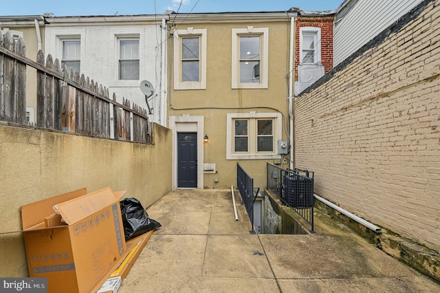 rear view of property featuring fence, a patio, and stucco siding