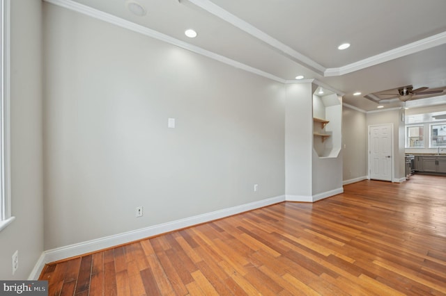 spare room with ornamental molding, light wood-style floors, and baseboards