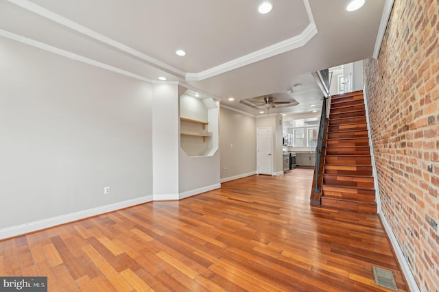 unfurnished living room with hardwood / wood-style flooring, stairs, baseboards, and crown molding