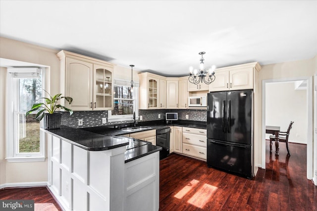 kitchen featuring cream cabinets, black appliances, an inviting chandelier, and decorative light fixtures