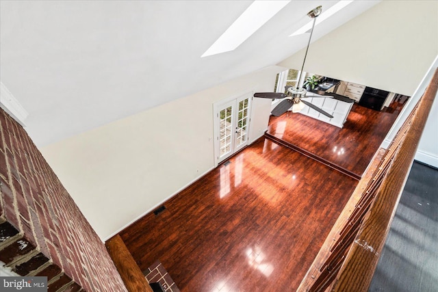 interior space featuring ceiling fan, wood-type flooring, french doors, and lofted ceiling with skylight