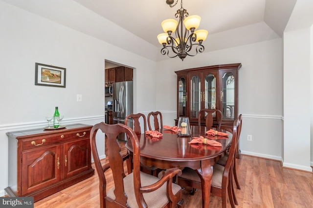 dining room featuring light wood-type flooring, a chandelier, and a raised ceiling