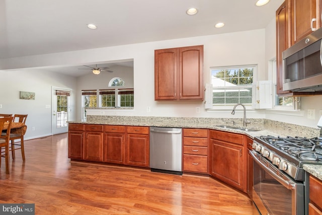 kitchen featuring hardwood / wood-style flooring, stainless steel appliances, light stone countertops, sink, and vaulted ceiling