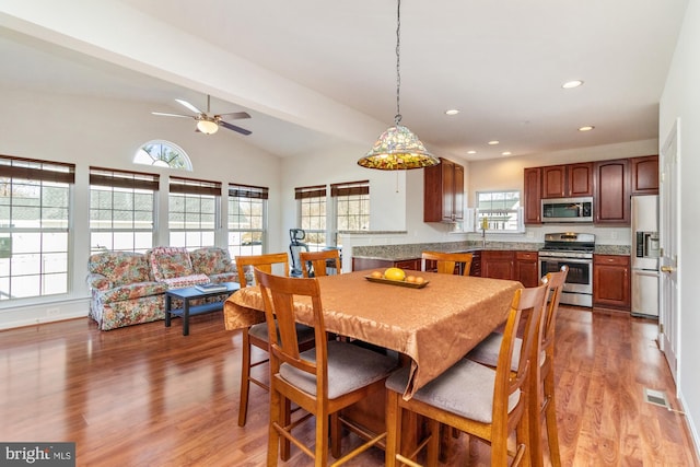 dining room featuring ceiling fan, lofted ceiling, wood-type flooring, and sink